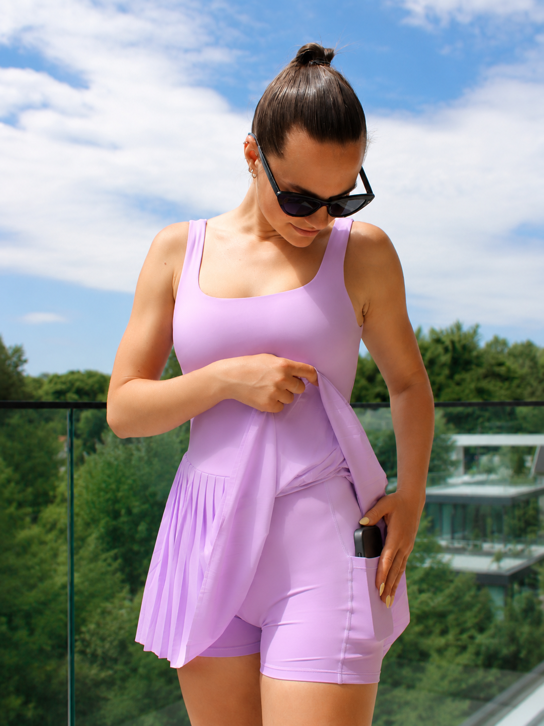 Woman wearing a purple dress with a skirt and white sneakers on a white background