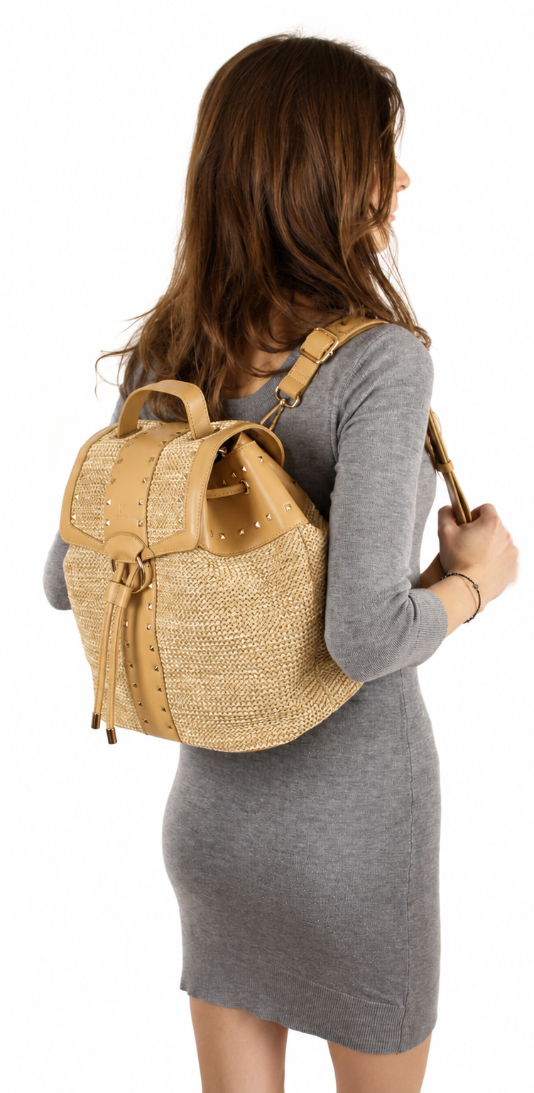 A woman wearing a gray long-sleeve dress is shown from the back, carrying a natural woven straw backpack with tan leather trim and straps against a plain white background.