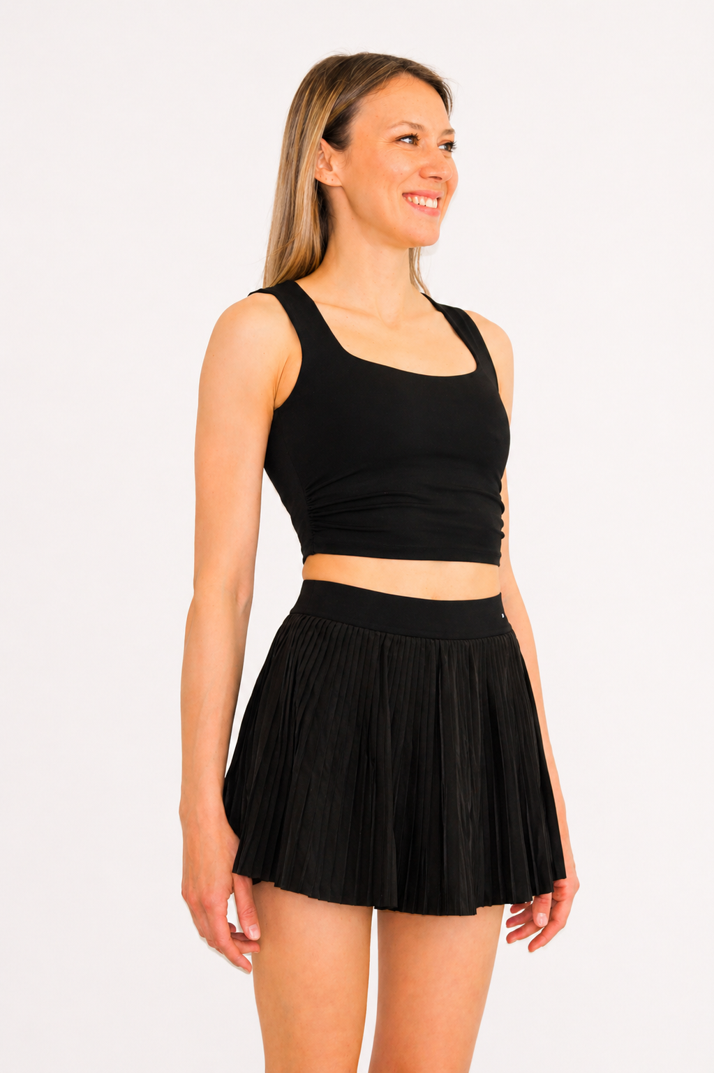 Woman wearing a black athletic top and skirt on a white background