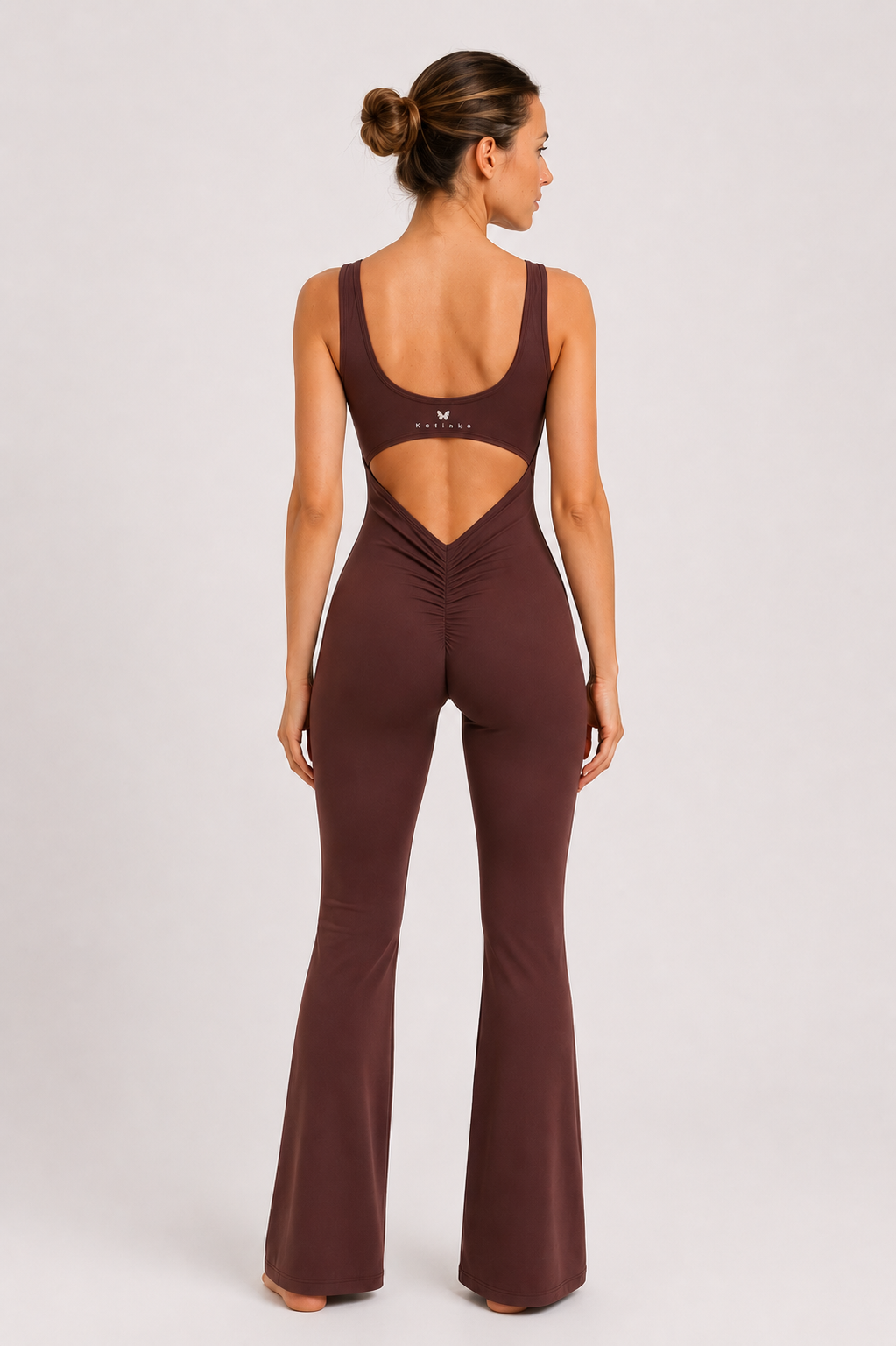 Woman wearing a brown jumpsuit with cut-out design on a white background
