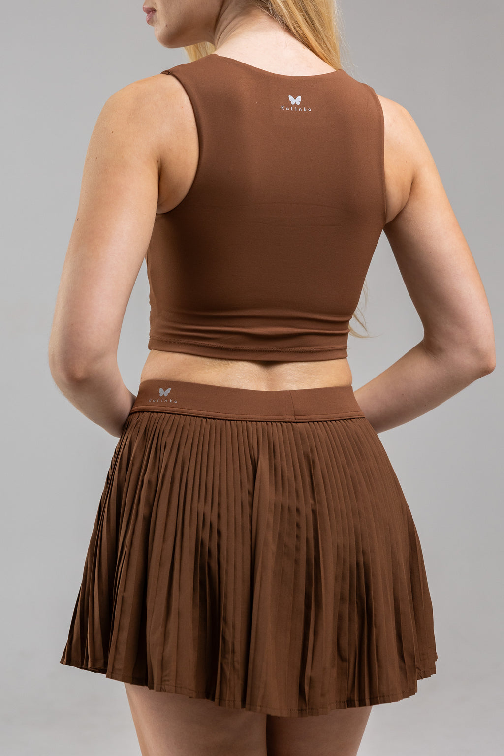 Brown athletic top and skirt set on a gray background